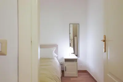 a white bedroom with a bed and a mirror at Labicana Apartment in Rome