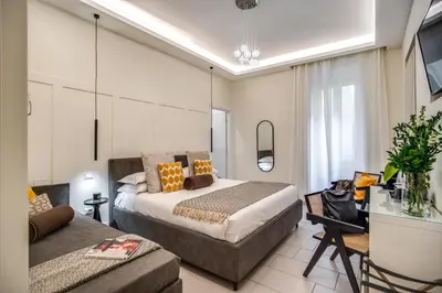 a bedroom with a bed and a couch and a tv at Borgognona Rooms in Rome
