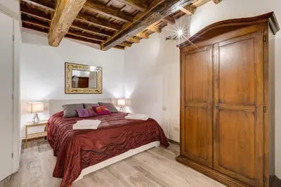 a bedroom with a bed and a large wooden closet at Pellegrino Campo de' Fiori Suite in Rome