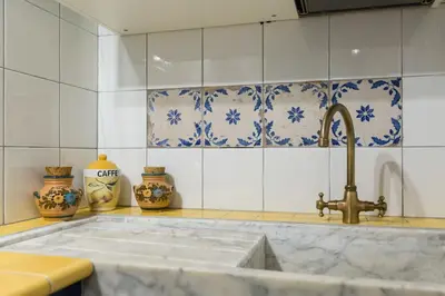a kitchen with a sink and blue and white tiles at Pellegrino Campo de' Fiori Suite in Rome