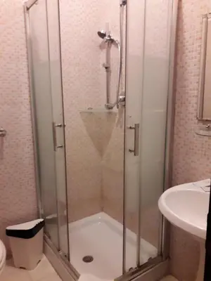 a shower with a glass door next to a sink at Botel Inn in Rome