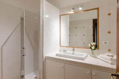 a white bathroom with a sink and a mirror at Relais Rasella 47 in Rome