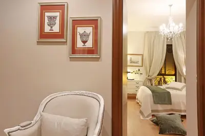 a bedroom with a bed and a chair and a chandelier at Daplace - Ottavia Apartment in Rome