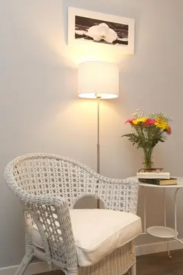 a white wicker chair next to a desk with a vase of flowers at A 2 Passi Dai Musei Luxury Guest House in Rome