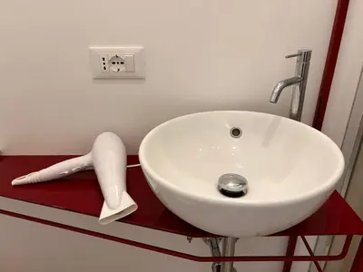 a white sink in a bathroom with a red counter at Suite Cardinale in Rome