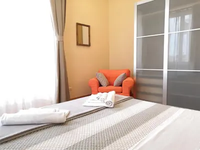 a bedroom with a bed and an orange chair at Tevere Rome Apartments in Rome