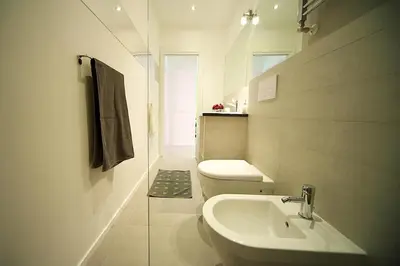 a white bathroom with a toilet and a sink at Lungotevere Holidays in Rome