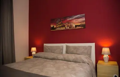 a bedroom with a bed with a red wall at Mikasa Piazza Bologna in Rome