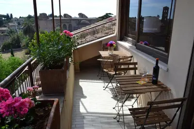 a balcony with tables and chairs and a bottle of wine at Penthouse Cardello Colosseum in Rome
