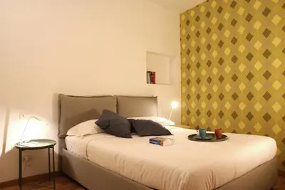 a bedroom with a bed with a yellow and white wall at La Controra Guesthouse Roma in Rome