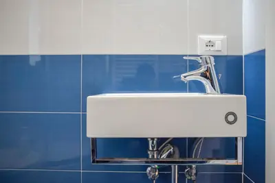 a white sink in a blue tiled bathroom at Penthouse Angelo Brunetti in Rome