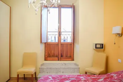 a bedroom with a bed and two chairs and a door at Penthouse Angelo Brunetti in Rome