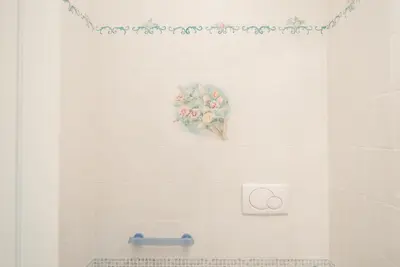 a white tiled bathroom with a flower painting on the wall at Frattina De Luxe in Rome