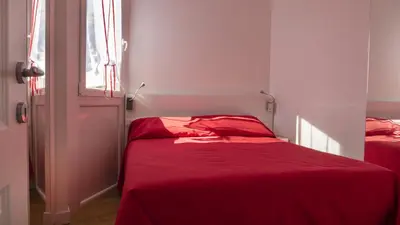 a bedroom with two beds with red sheets and a window at Garibaldi's Camp in Rome