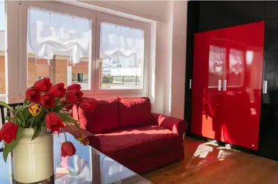 a living room with a red couch and a vase with red flowers at Garibaldi's Camp in Rome