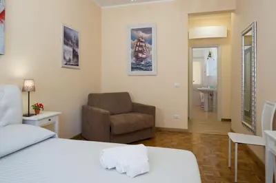 a bedroom with a bed and a chair and a window at Gregory House in Rome