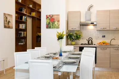 a dining room table with white chairs and a kitchen at Gregory House in Rome