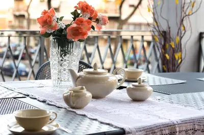 a table with cups and a vase with flowers on it at Gregory House in Rome