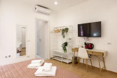 a room with a desk and a television on a wall at San Pietro Roma Suite in Rome