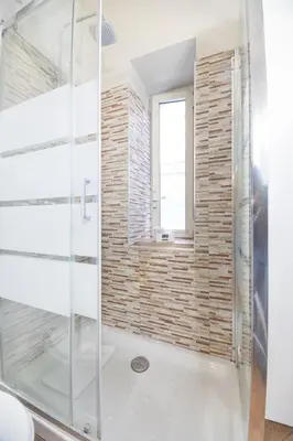 a glass shower in a bathroom with a brick wall at Le Piazze di Roma Sweet Apartment in Rome