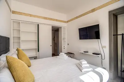 a bedroom with a white bed with yellow pillows and a tv at Magia at Colosseum in Rome