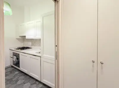 a kitchen with white cabinets and a stove at Modern Comfort, Poetic Charm in Rome