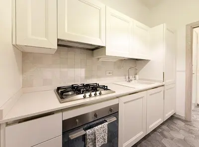 a white kitchen with a stove and white cabinets at Modern Comfort, Poetic Charm in Rome