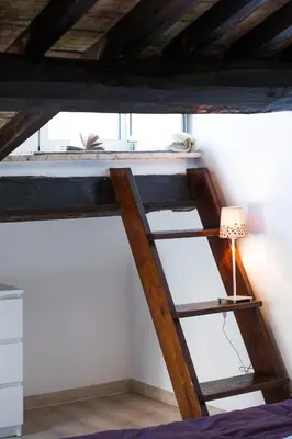 a ladder in a room with a bed and a lamp at Lo Chalet di Trastevere in Rome