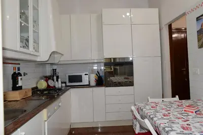 a white kitchen with white cabinets and a table at Emilio's Home in Rome