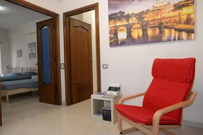 a living room with a red chair and a bed at Emilio's Home in Rome