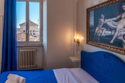 a bedroom with a blue bed and a painting on the wall at Moma Domus - Golden Keys Collection in Rome