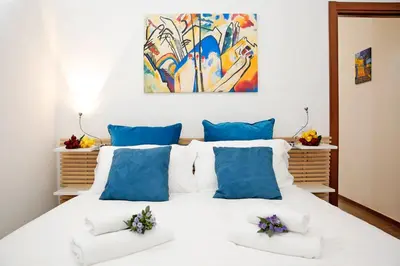a bedroom with a large white bed with blue pillows at Castel Sant Angelo's Harmonious Apartment in Rome