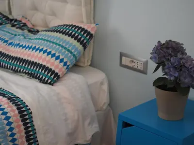 a bed with a pillow and a blue table with a plant at Bed and Breakfast New Morning Holiday in Rome