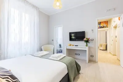 a white bedroom with a bed and a tv at Rome as you feel - Diocleziano Apartment in Rome