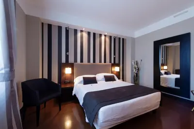 a hotel room with a large bed and a chair at TH Roma - Carpegna Palace in Rome