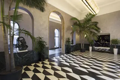 a lobby with palm trees and a checkered floor at TH Roma - Carpegna Palace in Rome