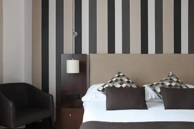 a bedroom with a bed and a chair at TH Roma - Carpegna Palace in Rome