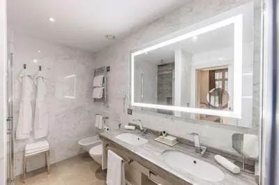 a bathroom with a sink and a mirror and a toilet at Aleph Rome Hotel, Curio Collection By Hilton in Rome
