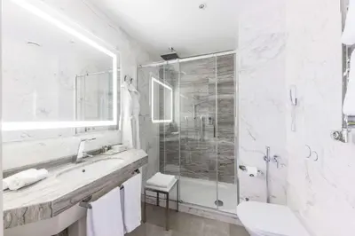 a white bathroom with a sink and a shower at Aleph Rome Hotel, Curio Collection By Hilton in Rome