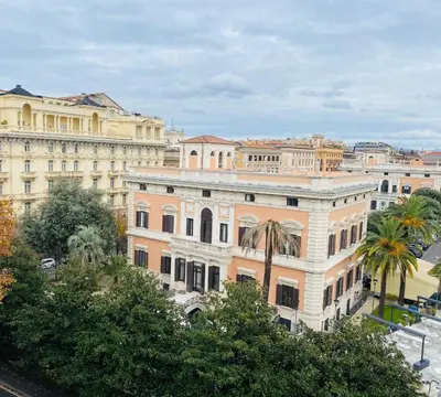 a large building with palm trees in front of it at Grand Hotel Palace Rome in Rome