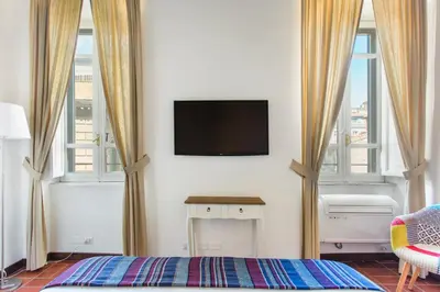 a bedroom with a tv on the wall and two windows at Andreasuite Trastevere in Rome