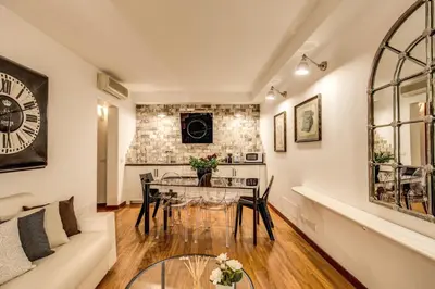 a living room with a table and a clock on the wall at Pantheon Miracle Suite in Rome