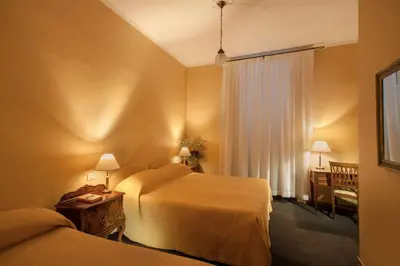 a hotel room with two beds and a desk at Orange Garden Guest House in Rome