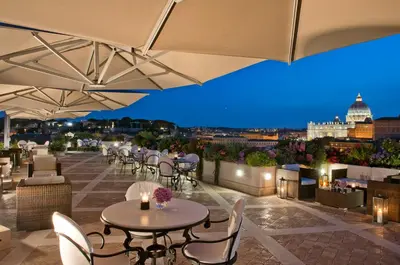 a rooftop patio with tables and chairs and a view of the city at Orange Garden Guest House in Rome