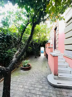 a brick walkway with trees and a pink building at Orange Garden Guest House in Rome
