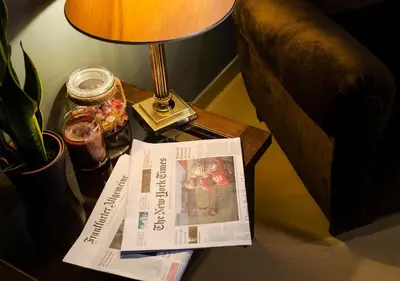 a newspaper on a table next to a lamp and a book at Eterna Roma in Rome