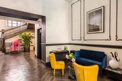 a living room with a blue couch and yellow chairs at Hotel The Haven Roma in Rome