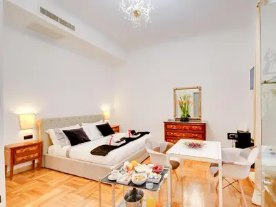 a white living room with a bed and a table at Queen Palace Suites in Rome