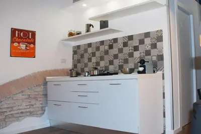 a kitchen with white cabinets and a brick wall at SuityRHome RioneMonti118 in Rome