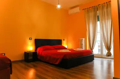 a bedroom with orange walls and a bed with red sheets at Nonna's house in Rome